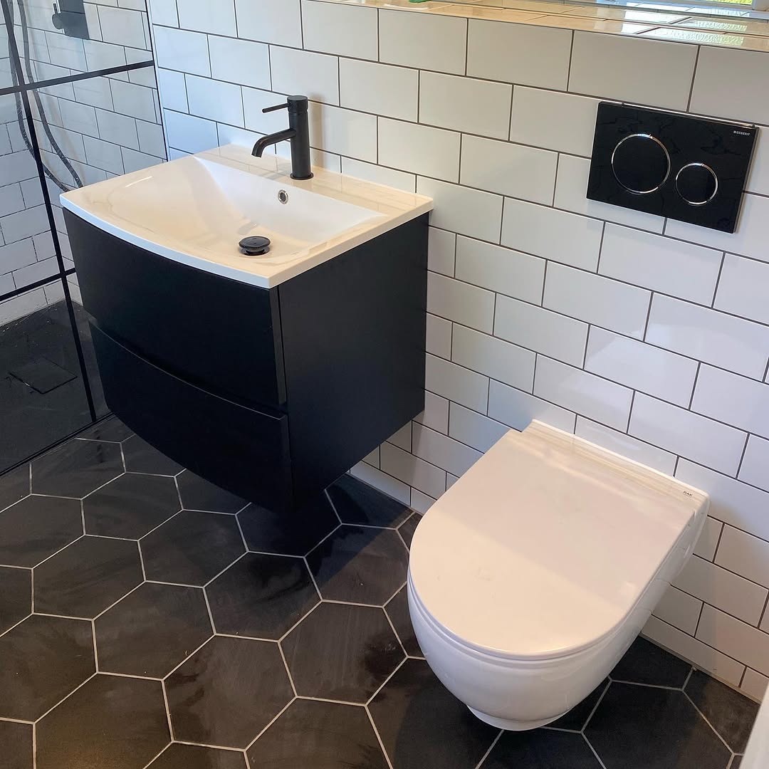 Modern en suite with matt black wall-hung vanity, white subway tiles, and dark hexagonal floor tiles
