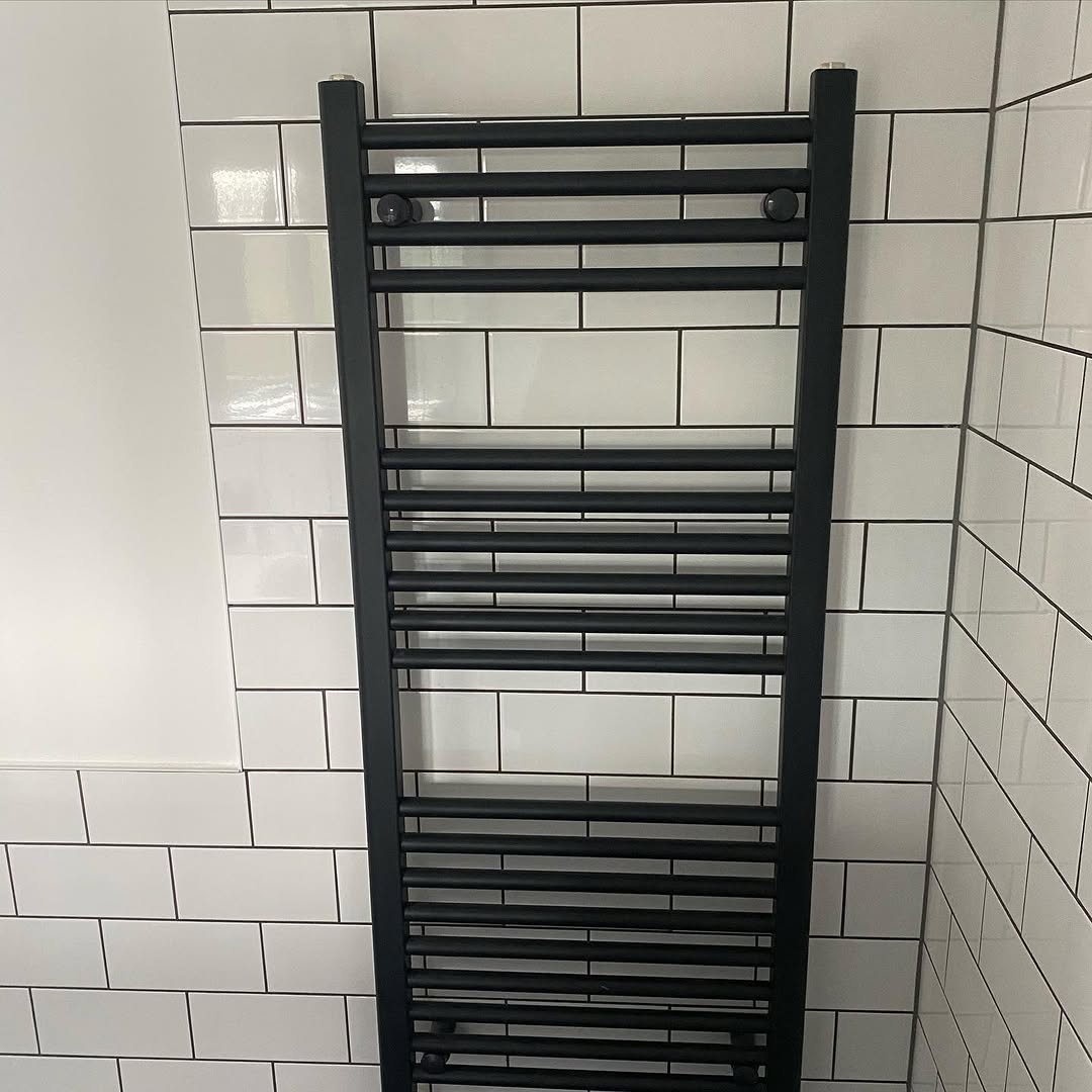 Detail of matt black shower head and rail against white subway tiles