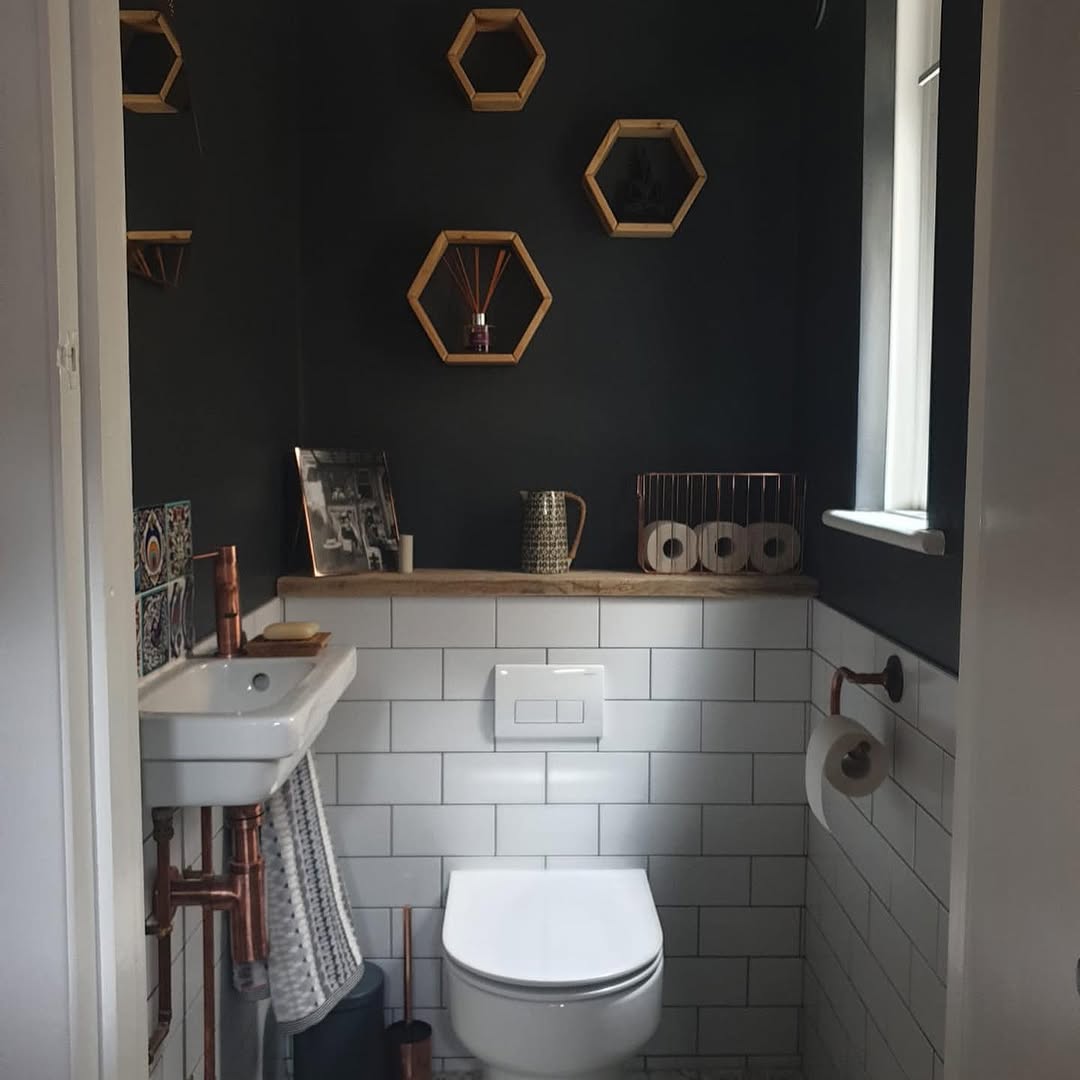 Bespoke cloakroom with dark olive walls, white metro tiles, exposed copper pipework, and hexagonal decorative shelves