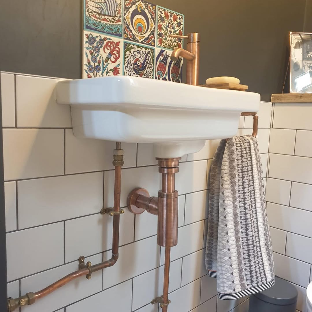 Alternative angle of the cloakroom showing copper tap detail, colourful ceramic tiles, and white metro tiling