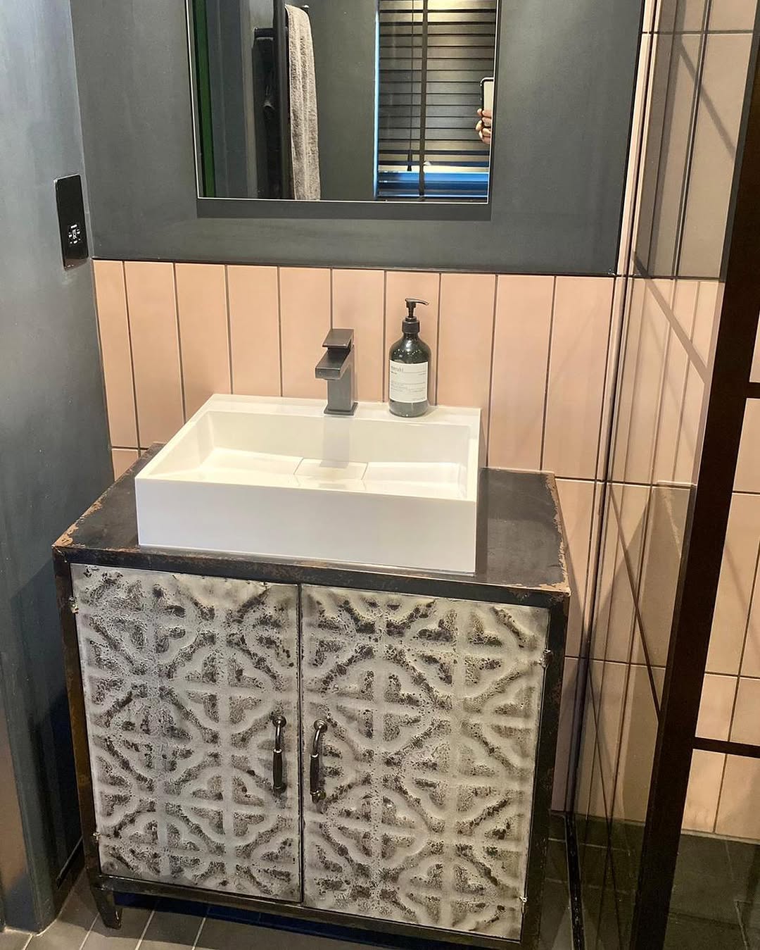 Patterned tile vanity unit with square vessel basin and matt black tap in dark-walled bathroom